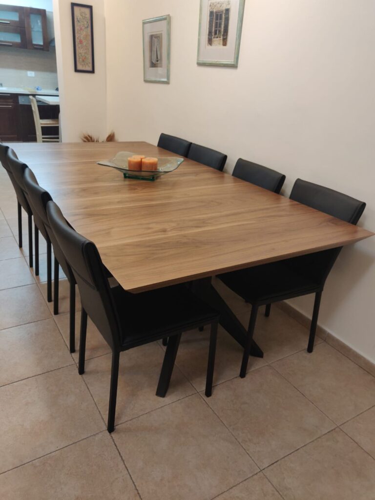 שולחן אוכל מעץ עם שישה כיסאות שחורים בחדר מואר
