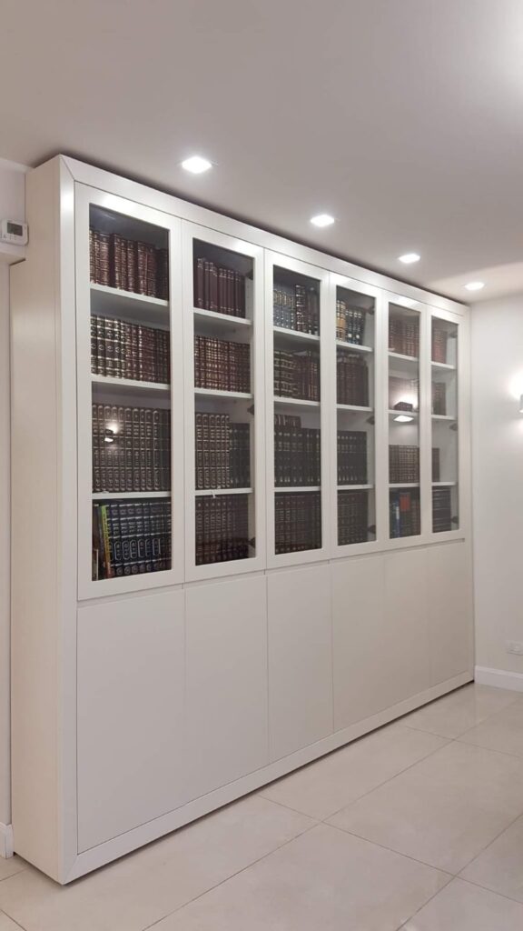 כוורת ספרים לבנה עם דלתות זכוכית וספרים כהים