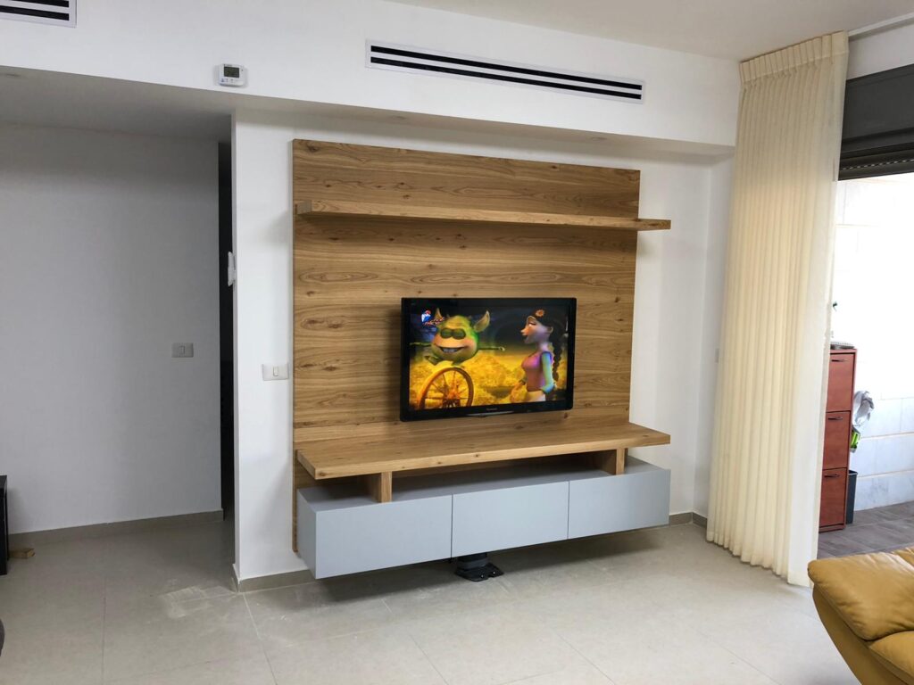 טלוויזיה תלויה על קיר עץ עם מדפים וארונית