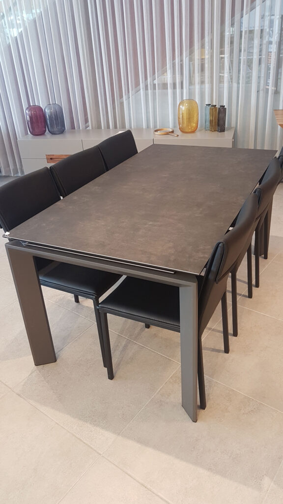 שולחן אוכל מודרני אפור עם שישה כיסאות שחורים בחדר מואר