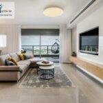 סלון מודרני עם ספה פינתית, טלוויזיה ומרפסת נוף עירוני
